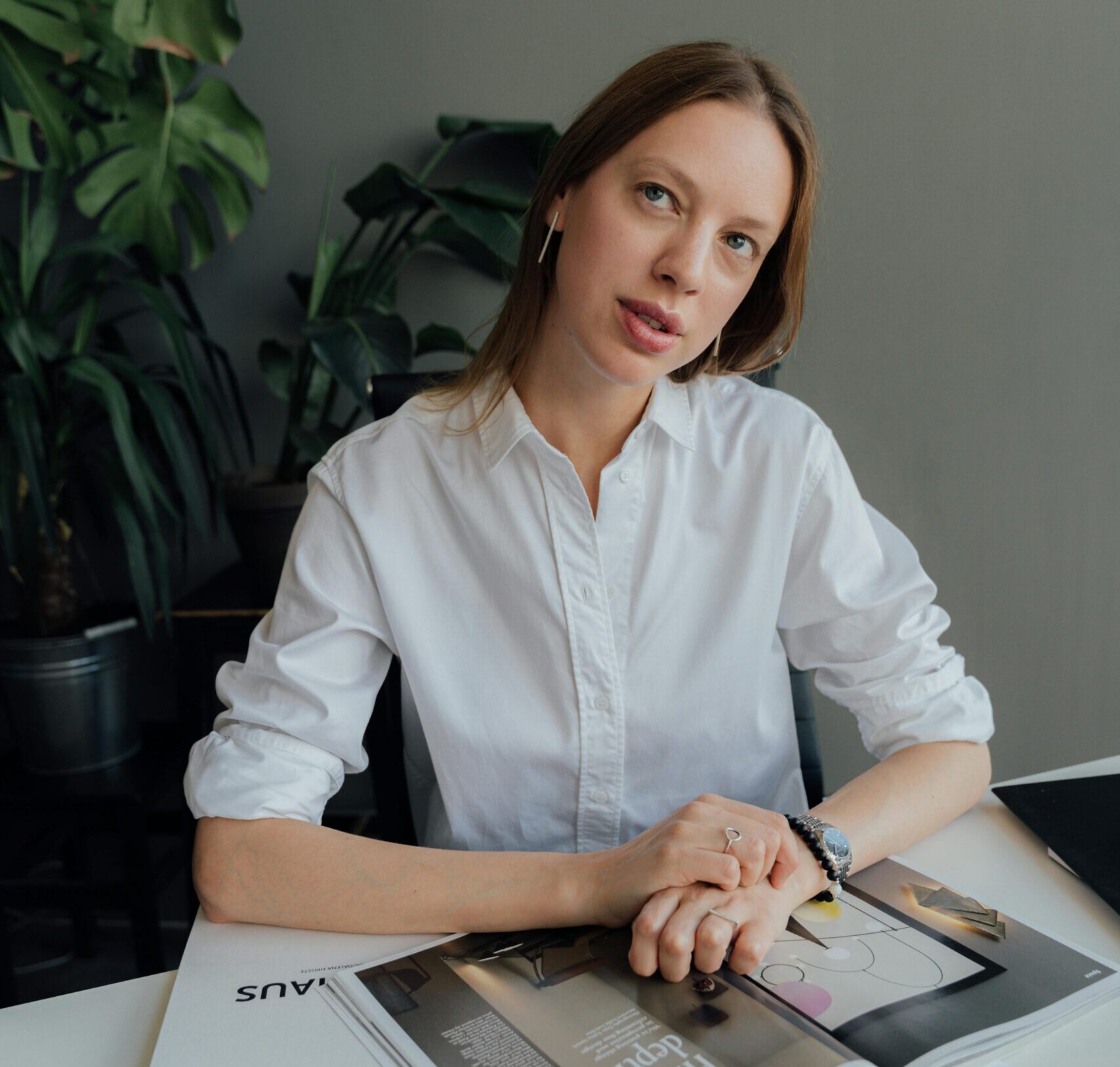 Confident woman in office setting, calmly contemplating work at her desk.